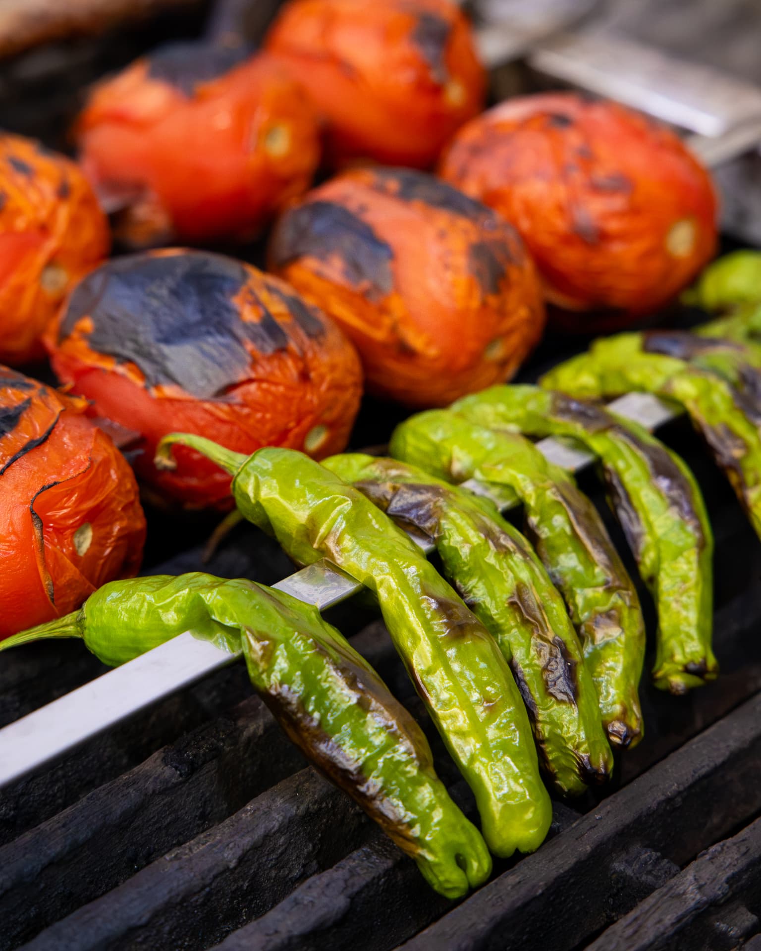 Grilled tomatoes and green peppers coming off the charcoal grill