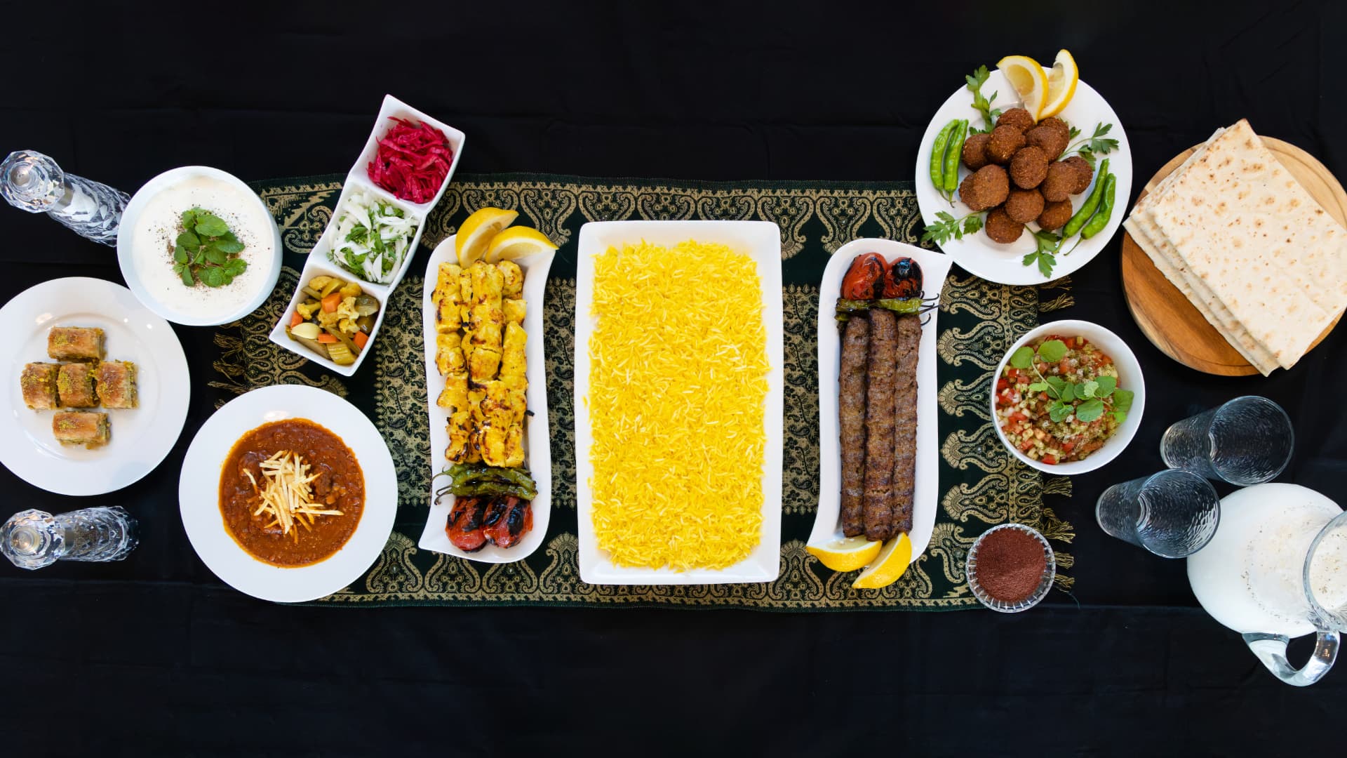 A full family-style Persian spread with kabobs, saffron rice, sides, lavash, and baklava
