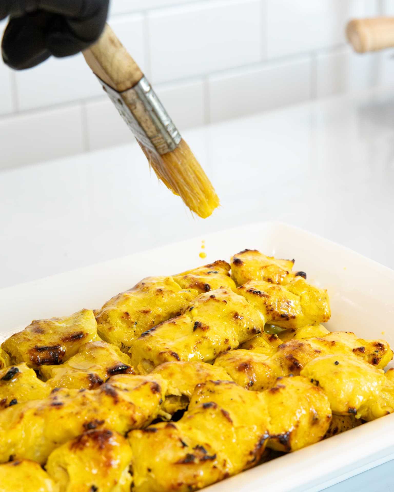 Saffron butter brushed over freshly grilled joojeh kabob in the kitchen